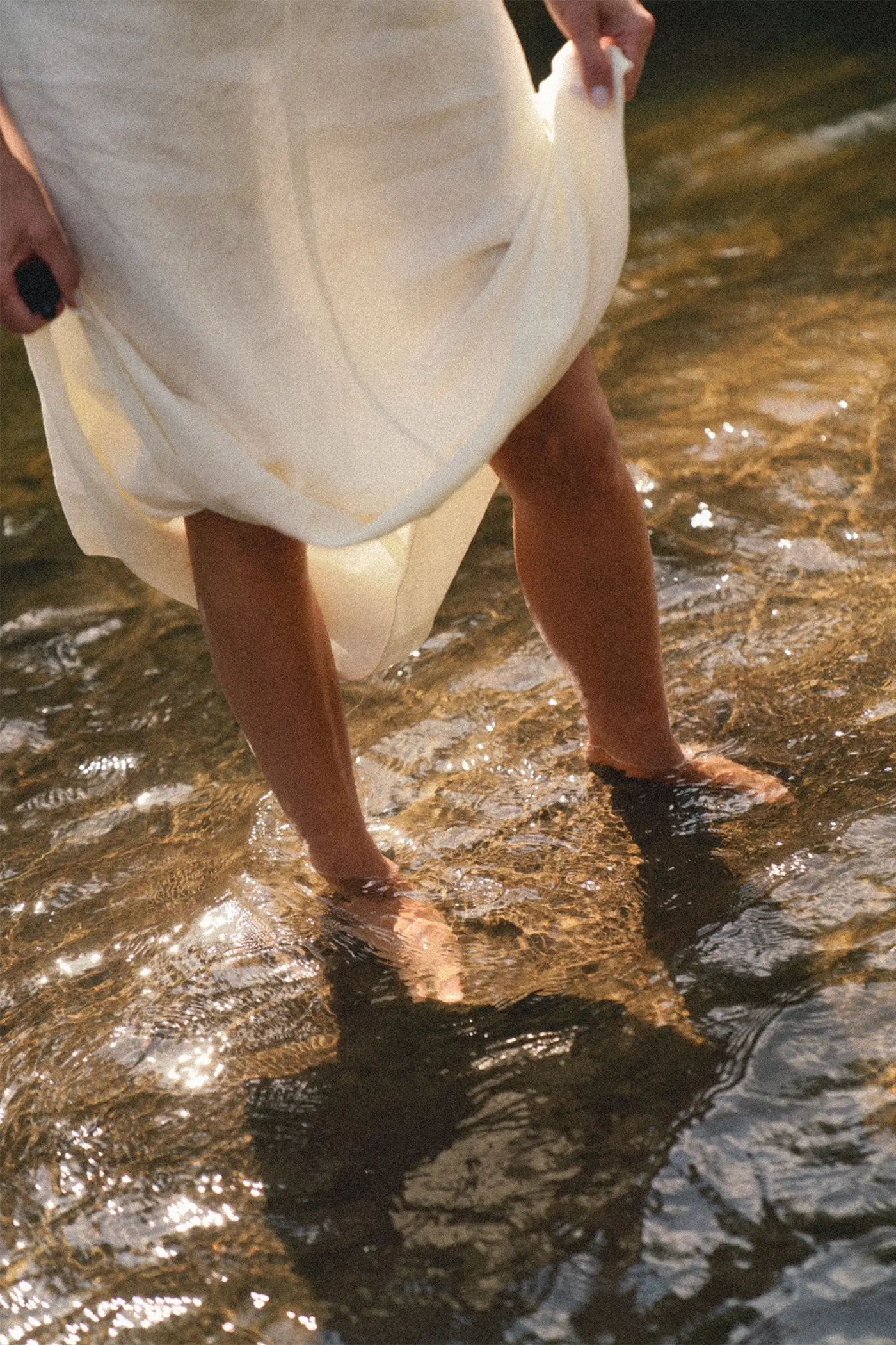 Stopy kobiety brodzącej w wodzie w białej sukni, jedność z naturą i filozofia slow beauty Tierra Natural