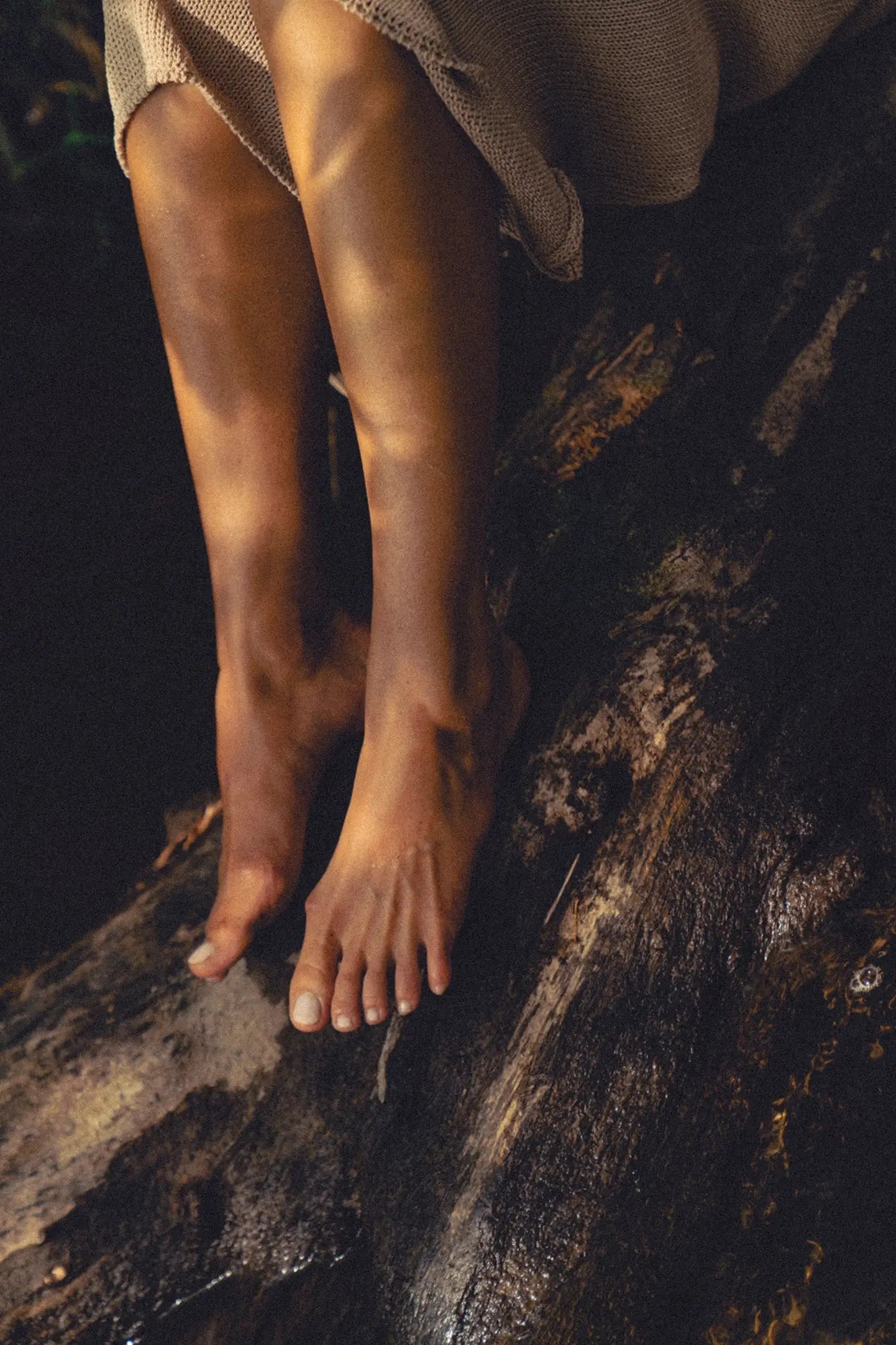 Stopy kobiety siedzącej na pniu drzewa w naturze, jedność z naturą i filozofia slow beauty Tierra Natural