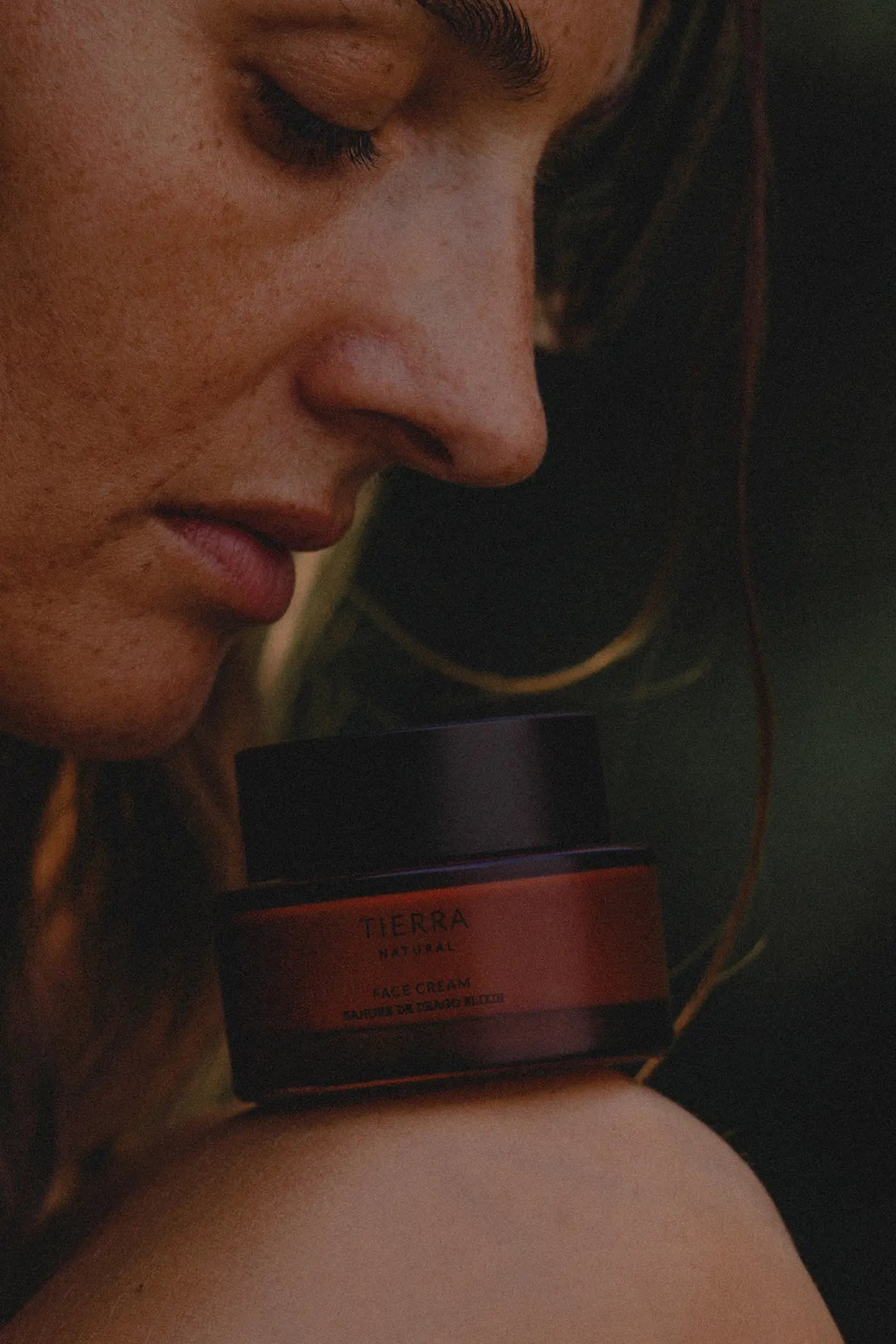 Kobieta trzymająca słoiczek Tierra Natural Face Cream przy twarzy - naturalny krem z roślinnymi składnikami, odżywiający i ujędrniający skórę.